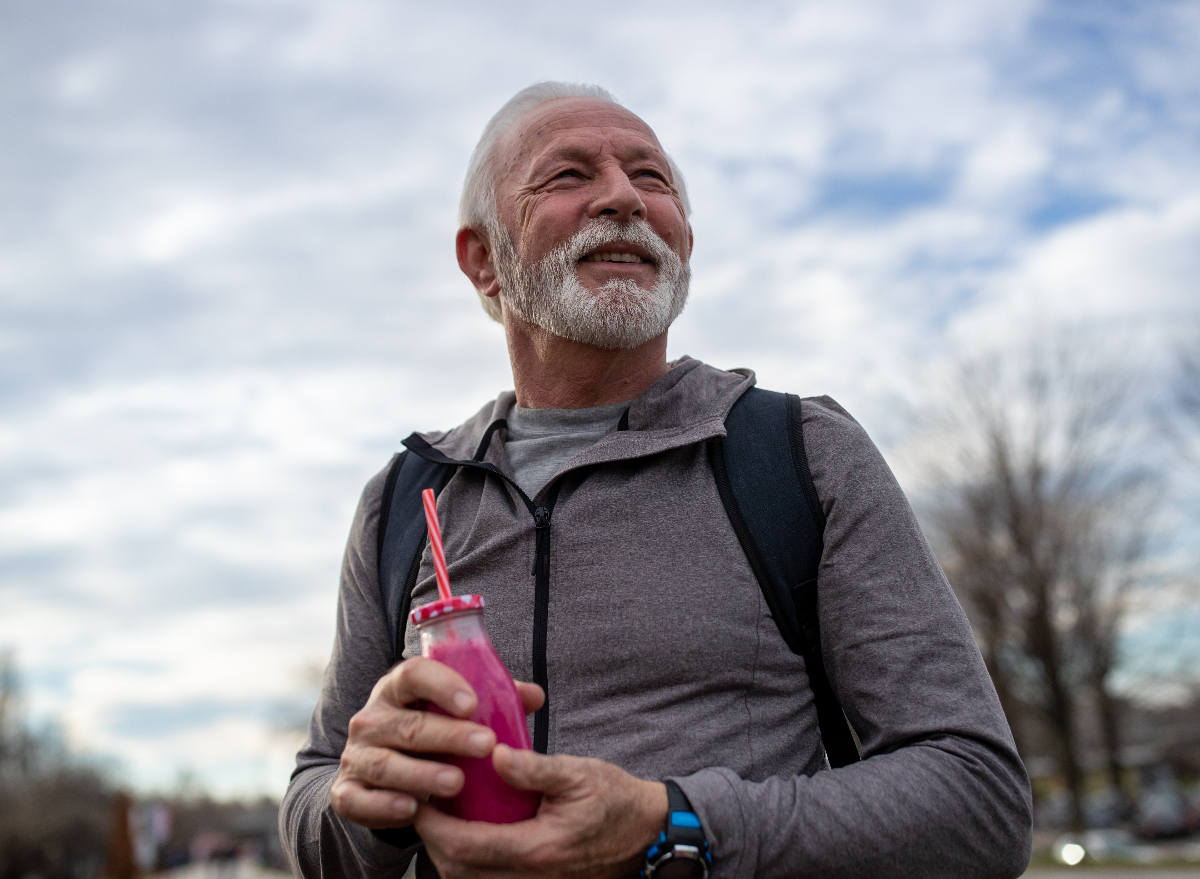 happy, athletic senior man holding pink smoothie