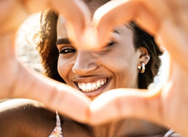 woman heart hands over face