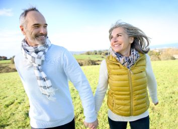 happy older couple walks in grassy area