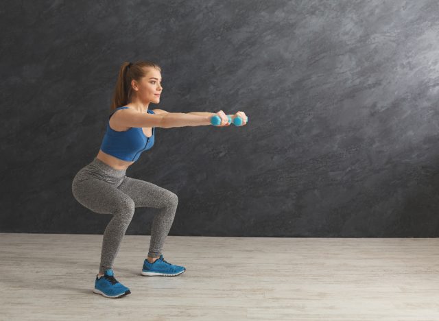 woman squats with dumbbells