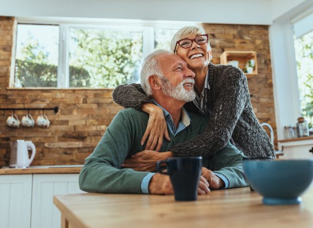 happy senior couple embraces in kitchen