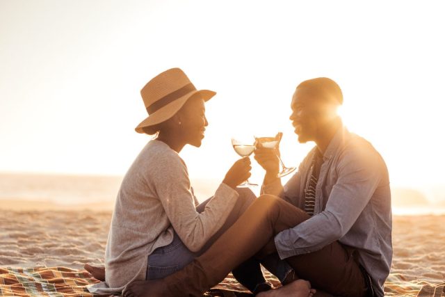 happy couple toasts wine glasses on beach