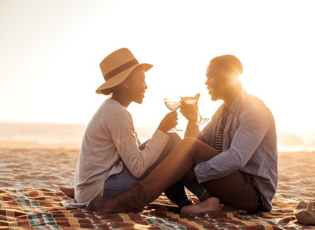 happy couple toasts wine glasses on beach