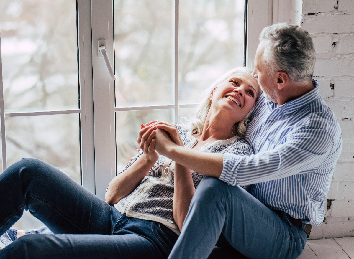 happy couple embraces next to bright window