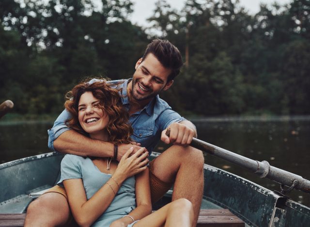 happy couple laughs and snuggles on canoe