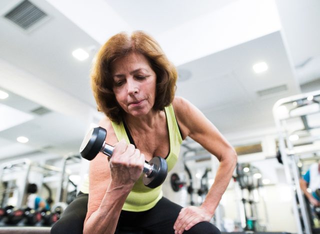 senior woman working out with weights in gym