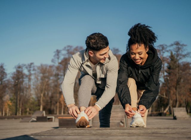 happy couple ties their sneakers outside