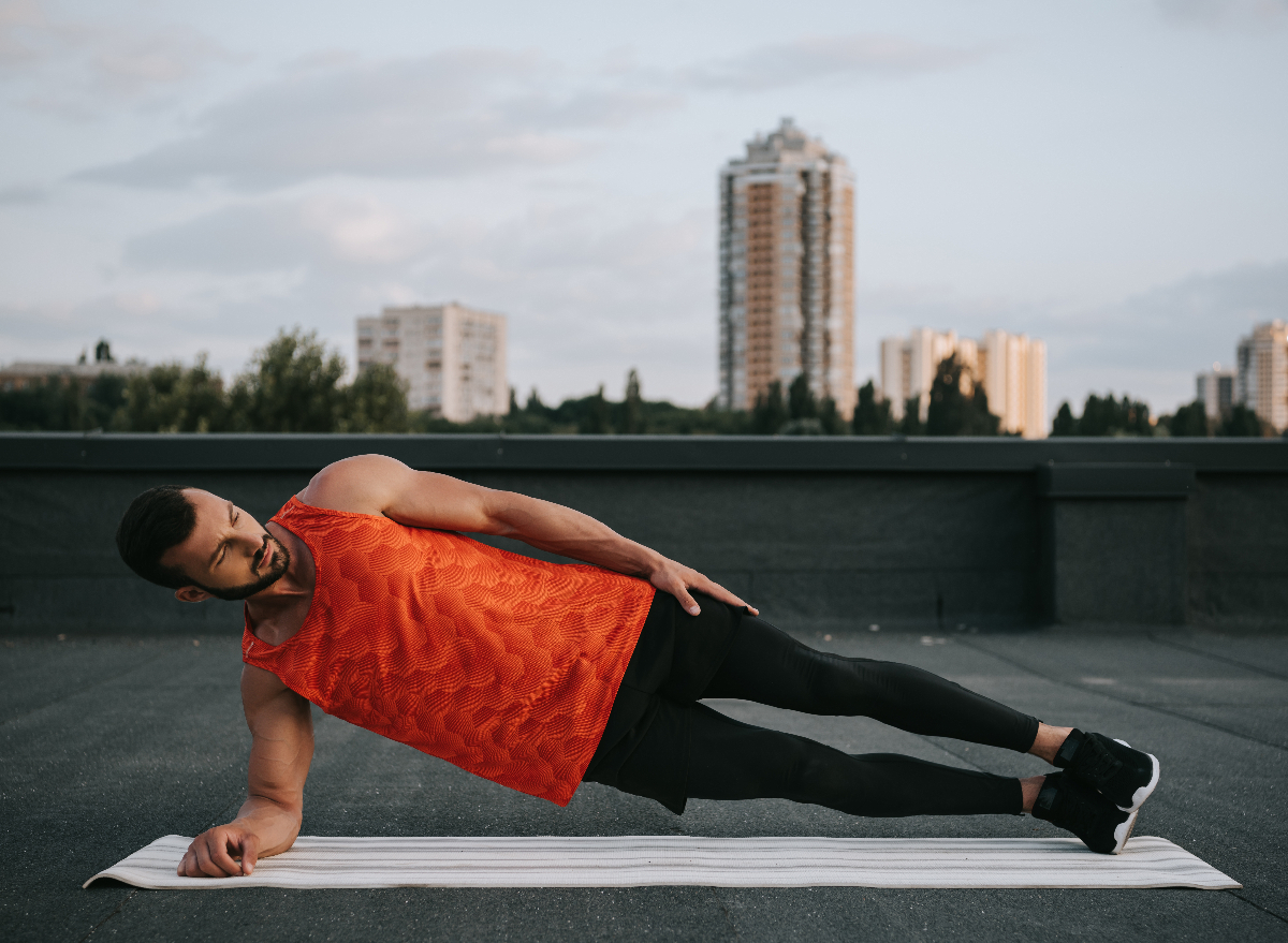 man doing side plank exercise on rooftop