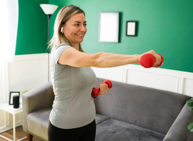 woman exercising with dumbbells in home