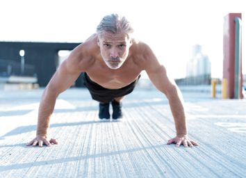 man in his 50s doing push-up on cement