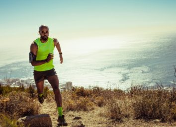 fit man running outdoors up hill by ocean