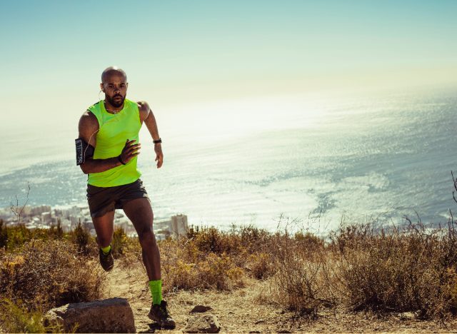 fit man running outdoors up hill by ocean