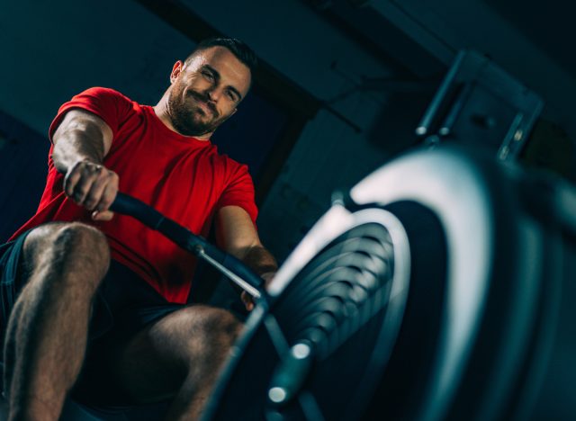 fit man using a rowing machine to melt belly fat fast