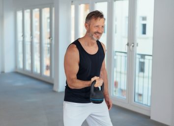 man doing kettlebell workout in bright apartment
