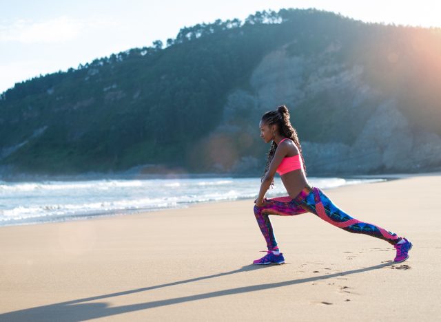 woman doing walking lunges on the beach