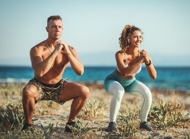 couple does squats at beach