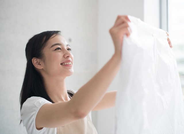 happy woman holding up clean piece of laundry