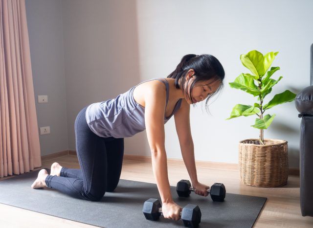 woman doing tabletop exercise with weights on yoga mat