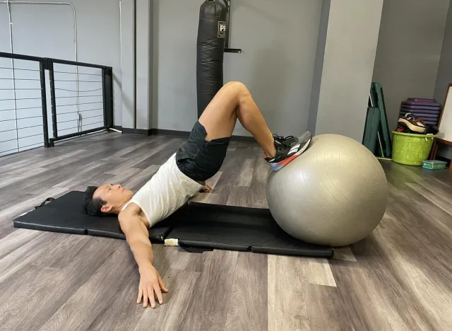 trainer working out with stability ball on mat