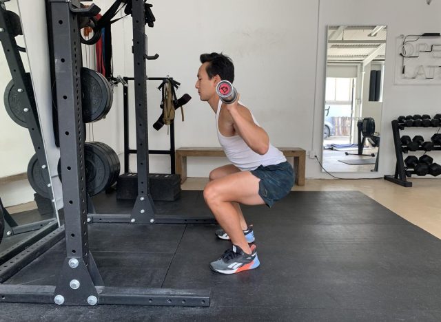 trainer doing barbell back squat