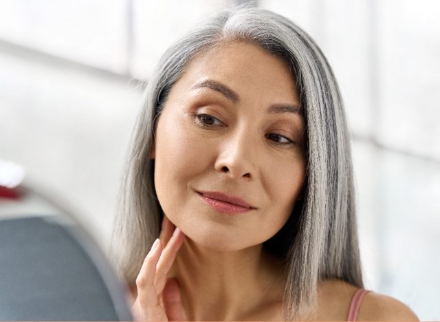 older woman admires her glowing skin in mirror