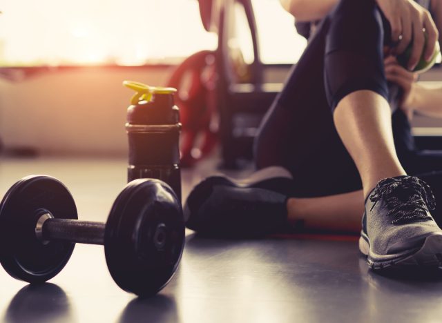 woman sitting with dumbbell at gym