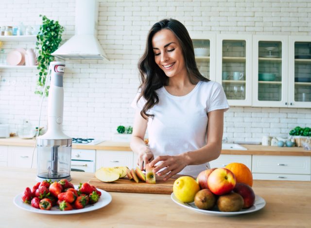 happy woman cuts fruit in bright kitchen