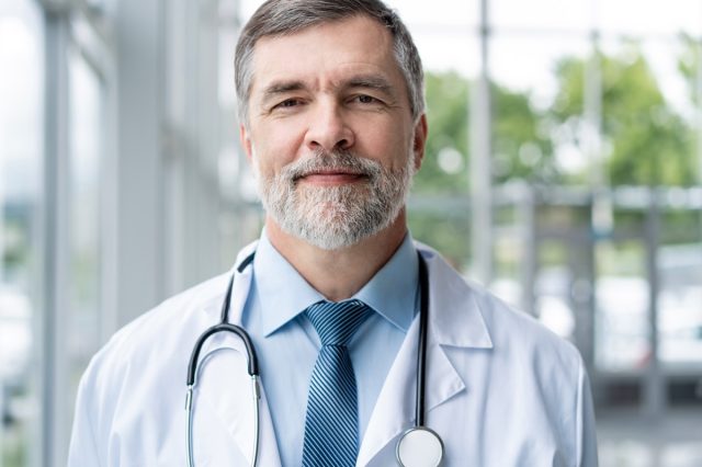 Confident smiling doctor posing in hospital.