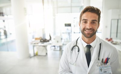 Portrait of a smiling male doctor standing in a hospital lobby