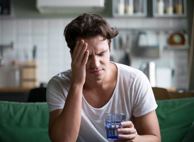 man with headache holding water