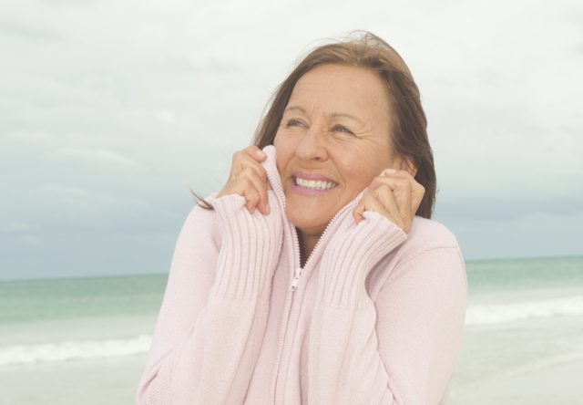 Mature woman cold on the beach.