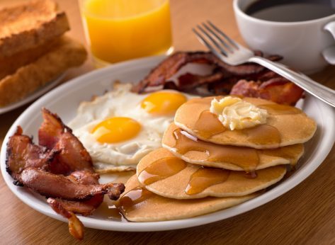 pancakes, bacon, eggs, toast, juice, and coffee