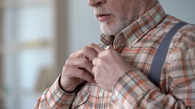 Senior man buttoning his shirt.