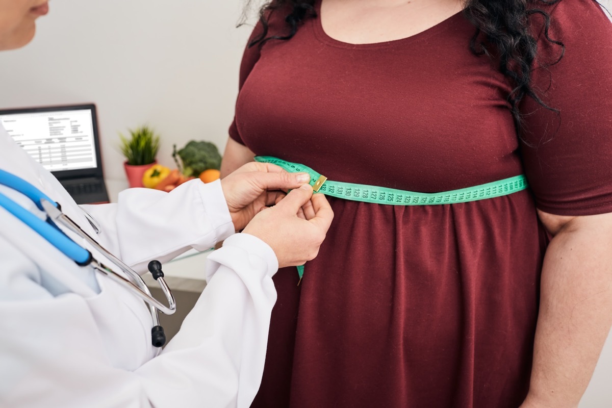 Nutritionist inspecting a woman's waist using a meter tape