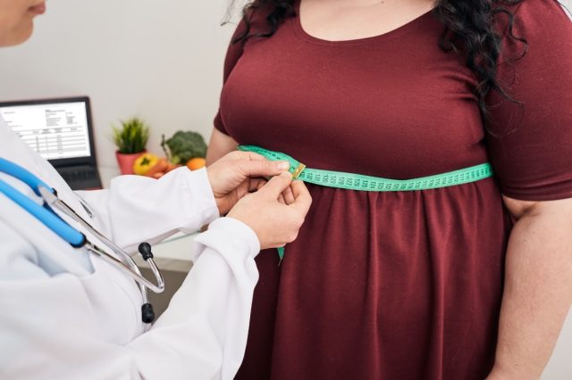 Nutricionista inspeccionando la cintura de una mujer usando una cinta métrica