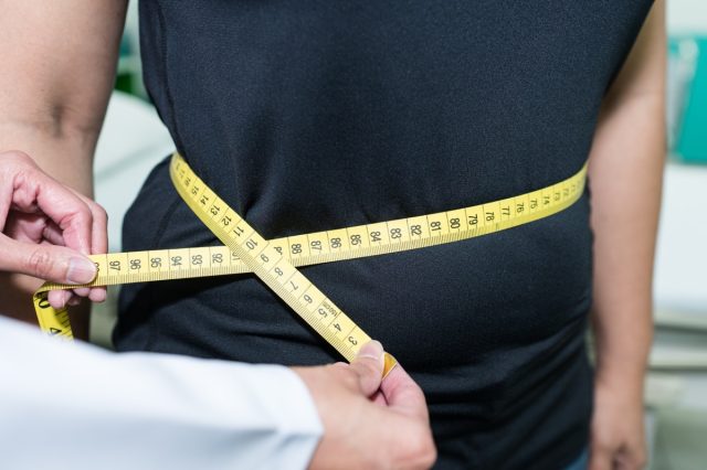 Doctor measuring waist of patients, checking for Body mass index (BMI).
