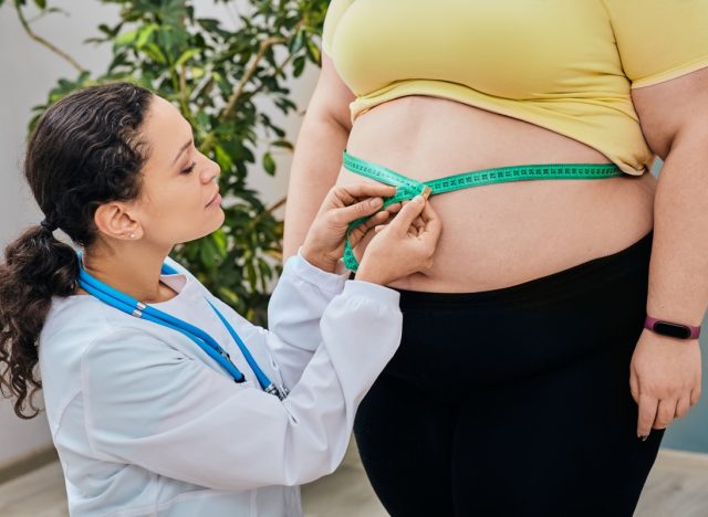 Nutritionist inspecting a woman's waist using a measuring tape to prescribe a weight loss diet