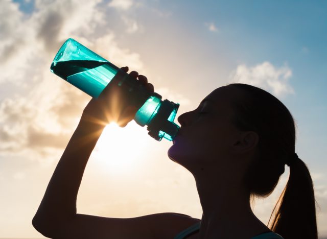 woman drinking water while training for long-distance running