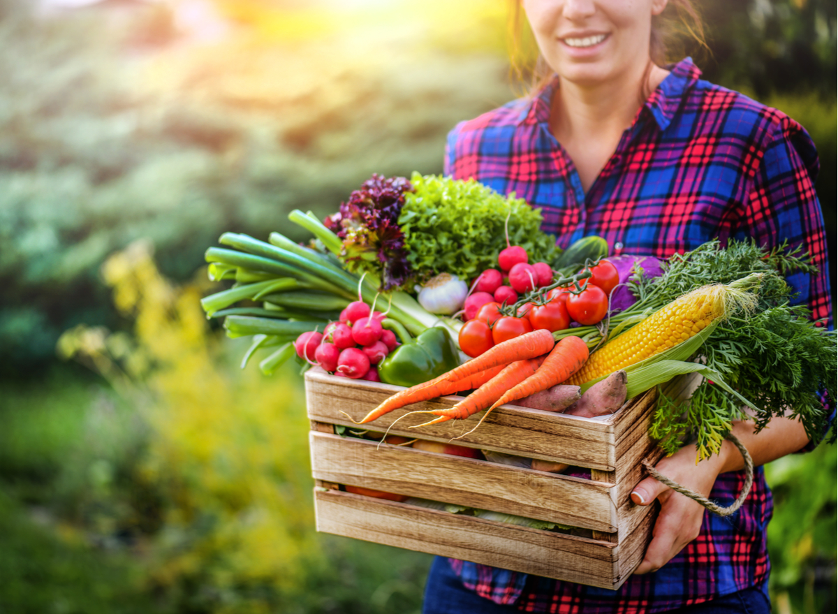 woman holding box of vegetables