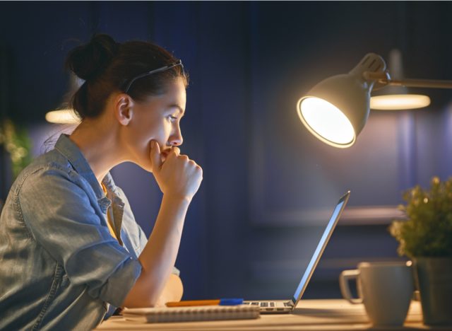 woman working on laptop next to light