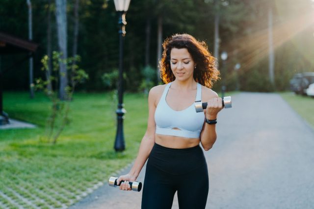 woman walks outside with dumbbells