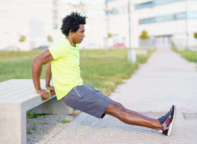 man performing bodyweight dip outside along walking route