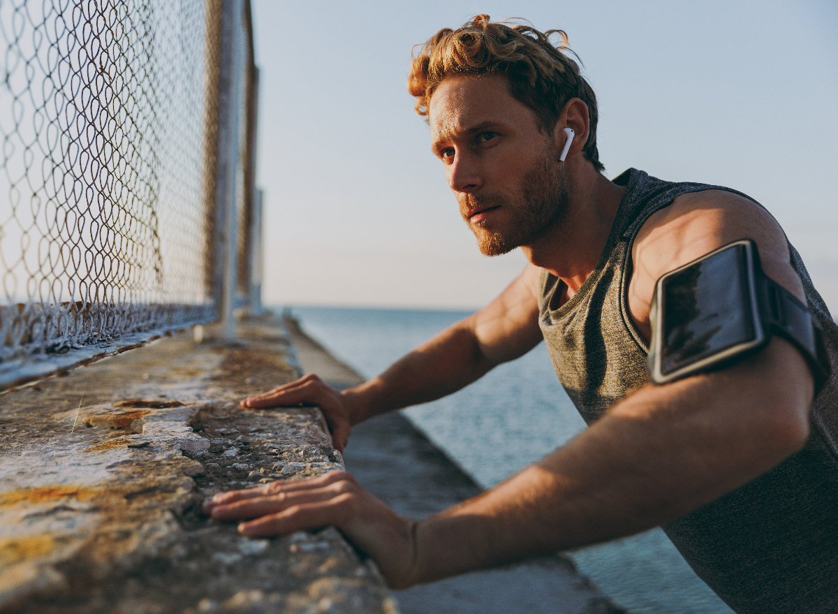 man warms up for run outdoors by water