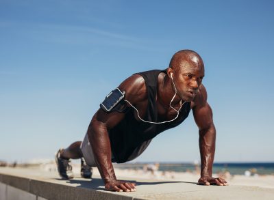 fit man doing pushup at beach on sunny day