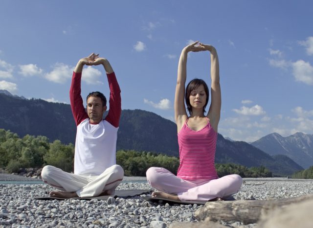 couple doing seated with arms overhead yoga pose