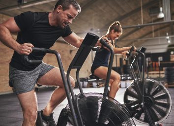 man doing intense workout on air bike to lose spare tire fat