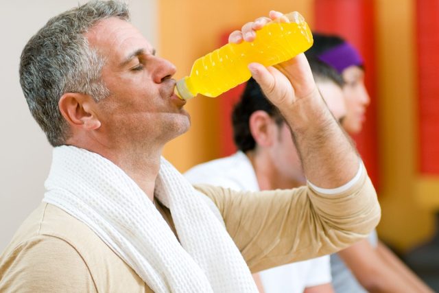 man drinking yellow energy drink mid workout