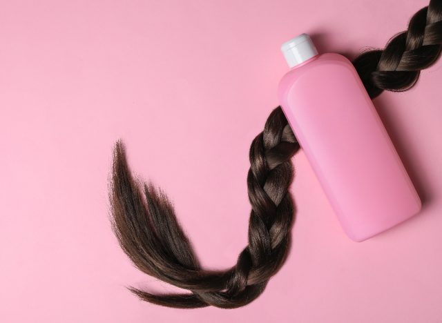 hair product next to long braid on pink backdrop