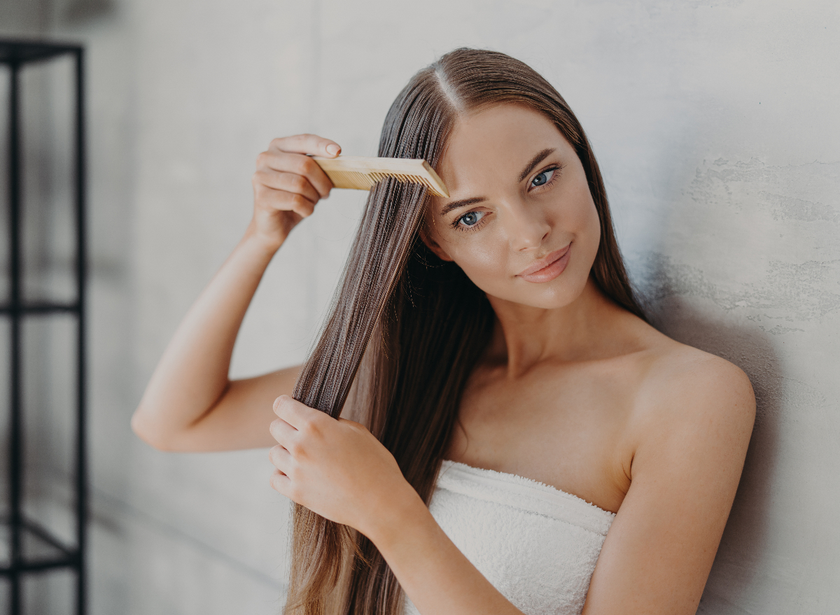 woman brushes long, brown hair