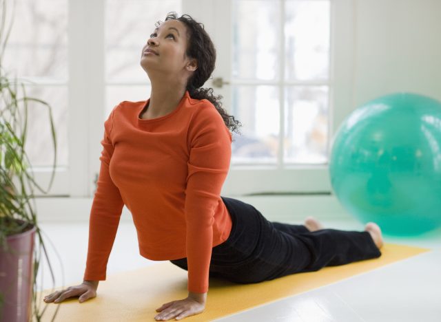 woman doing cobra pose on mat